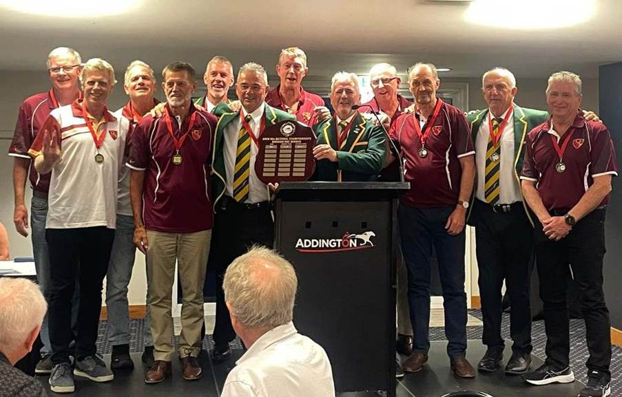 Group of cricket players celebrating with medals and a trophy at an awards ceremony.